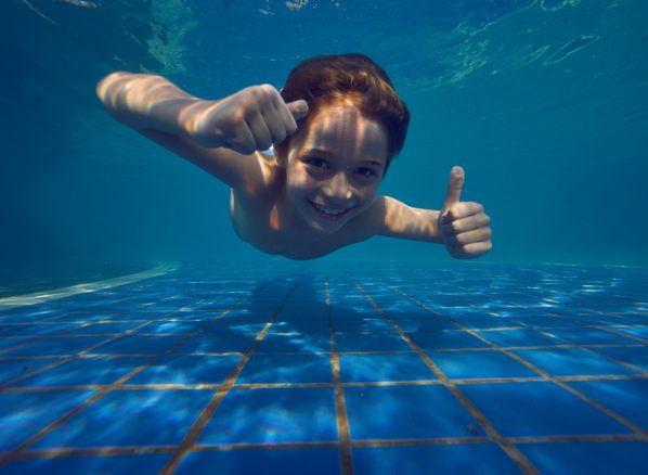 Criança mergulhando na piscina